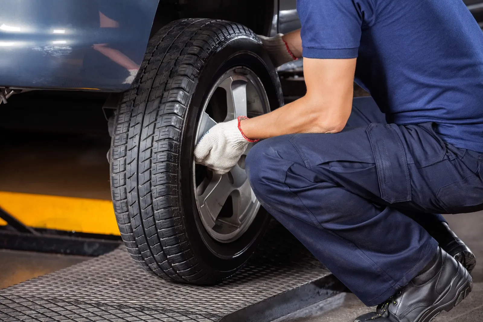 Car mechanic at TS Auto Repairs fixing a tyre back onto a car